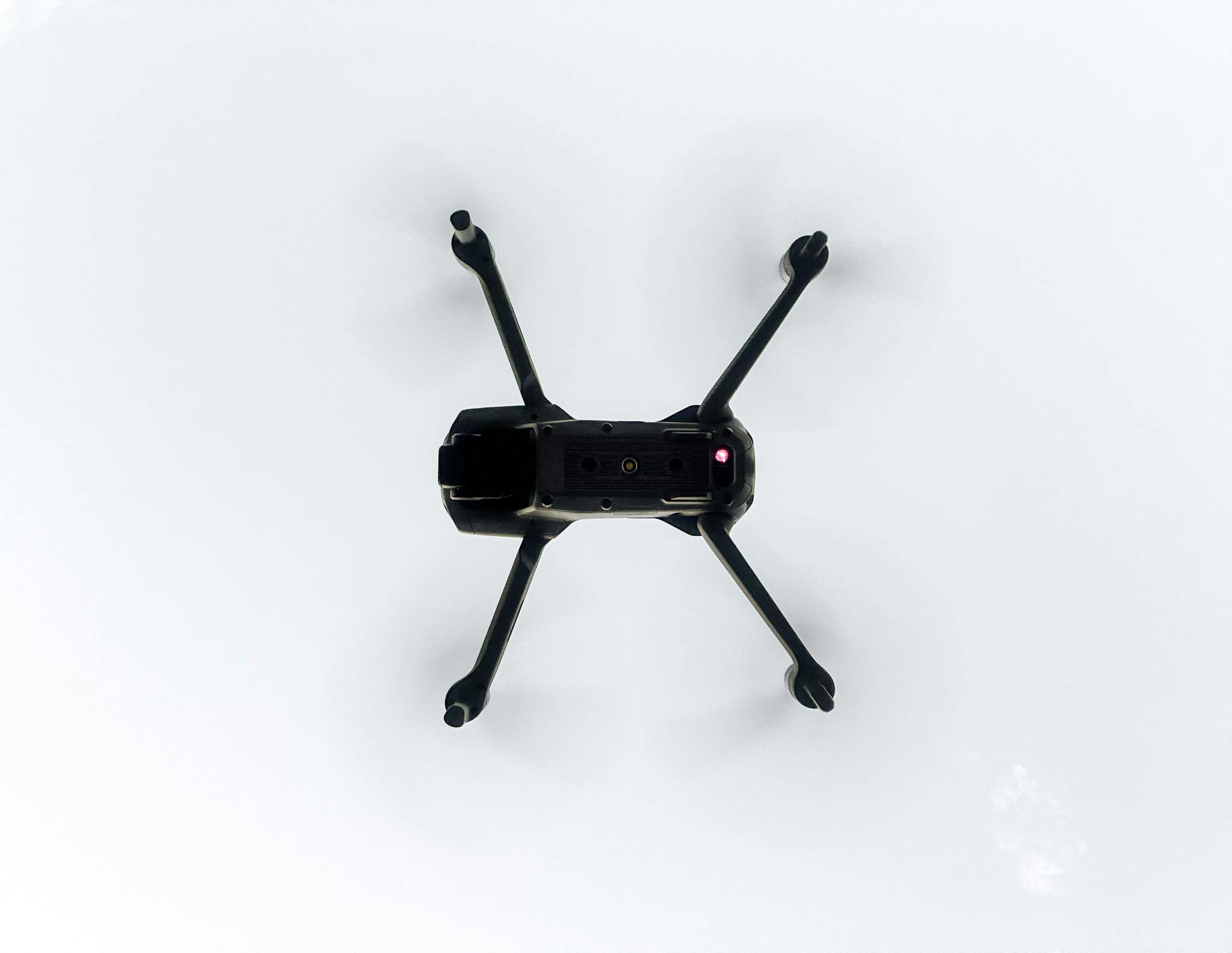 Overhead view of a drone flying in a clear sky, showcasing modern technology.