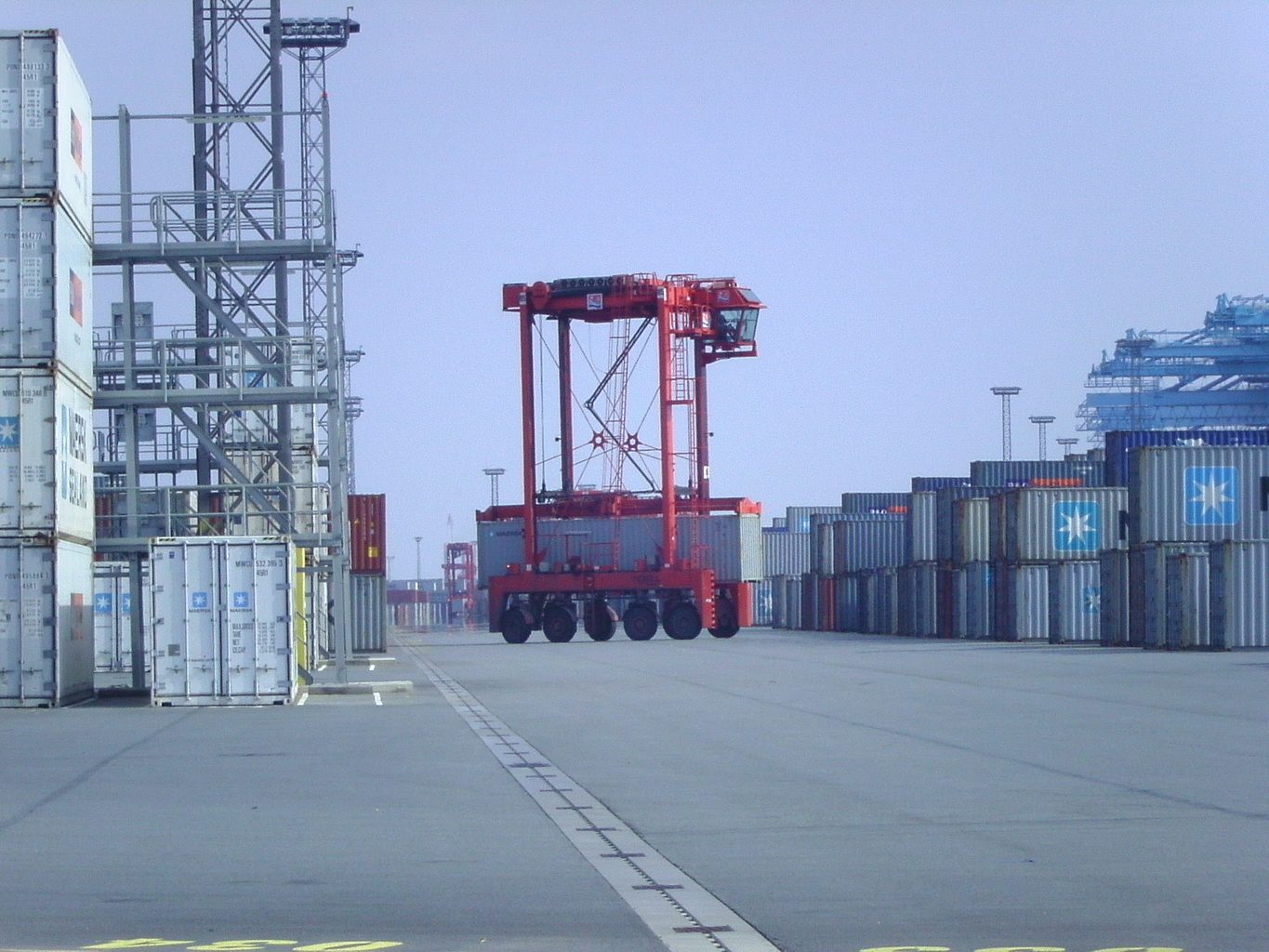 Straddle carrier amid steel and stacked containers